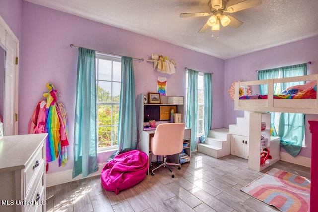 bedroom featuring a textured ceiling, light wood-type flooring, and ceiling fan