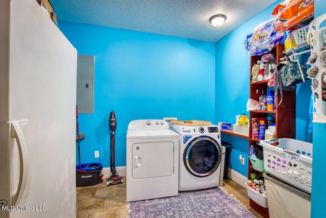 clothes washing area featuring washing machine and dryer, electric panel, and a textured ceiling