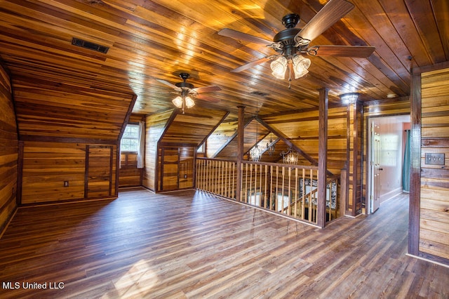 additional living space featuring dark wood-type flooring, lofted ceiling, wood ceiling, wood walls, and ceiling fan