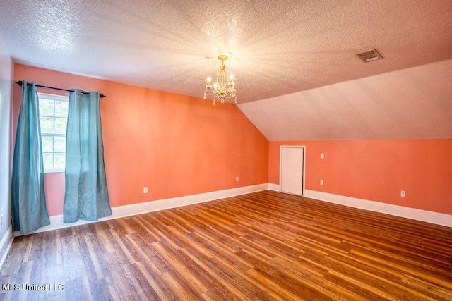 bonus room featuring a notable chandelier, wood-type flooring, a textured ceiling, and vaulted ceiling