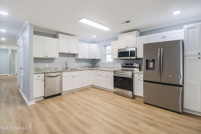 kitchen with light stone countertops, appliances with stainless steel finishes, sink, light hardwood / wood-style floors, and white cabinetry