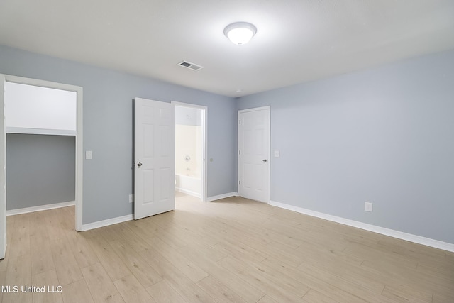 unfurnished bedroom featuring light wood-type flooring, a spacious closet, and a closet