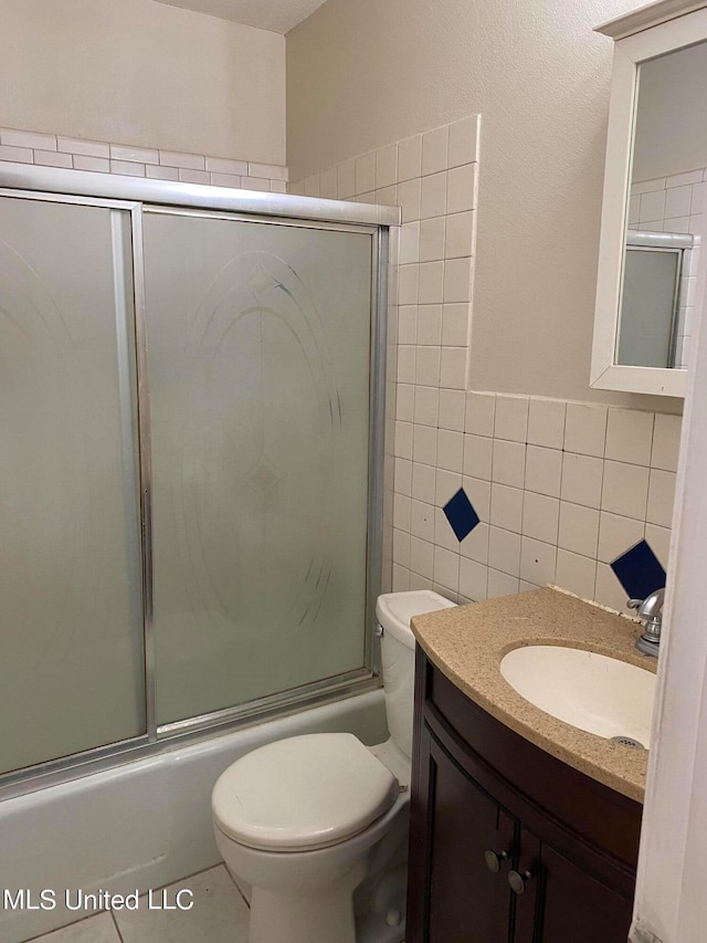 full bathroom featuring toilet, tile patterned flooring, vanity, tile walls, and shower / bath combination with glass door