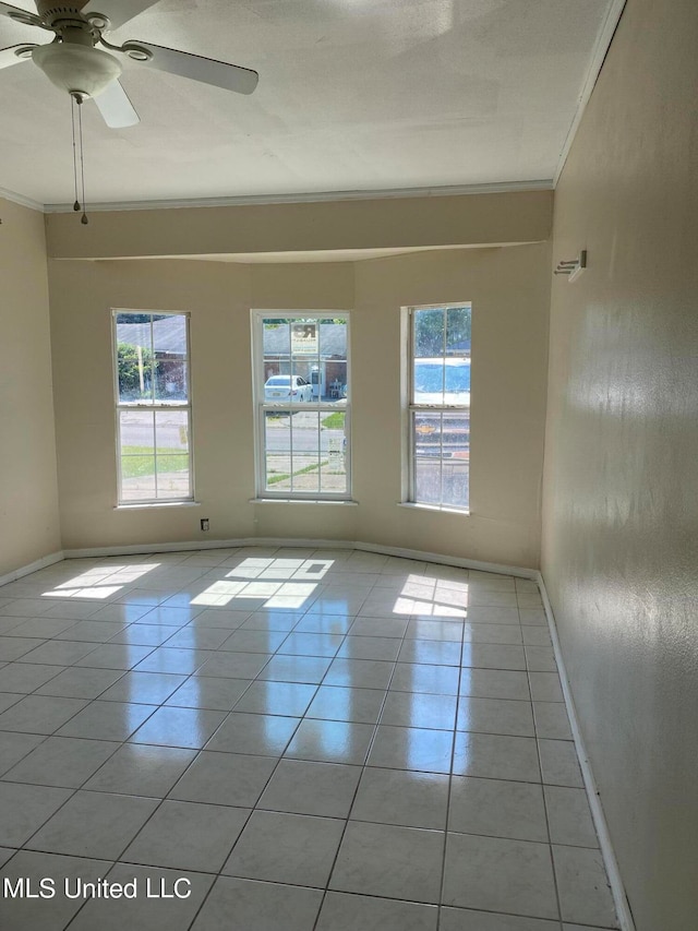 empty room featuring ornamental molding, ceiling fan, plenty of natural light, and light tile patterned floors