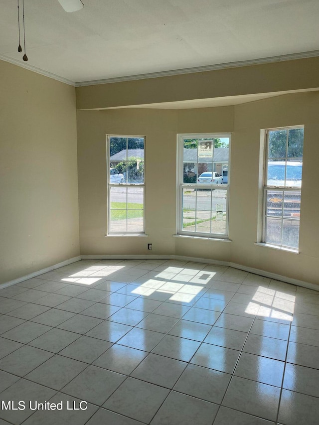 tiled empty room featuring a wealth of natural light and crown molding