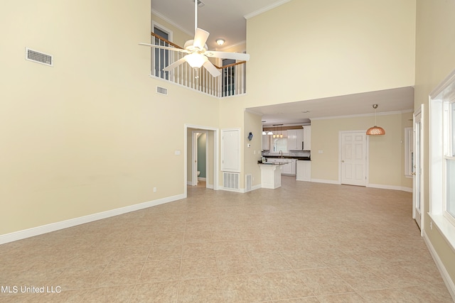 unfurnished living room with sink, crown molding, a high ceiling, and ceiling fan