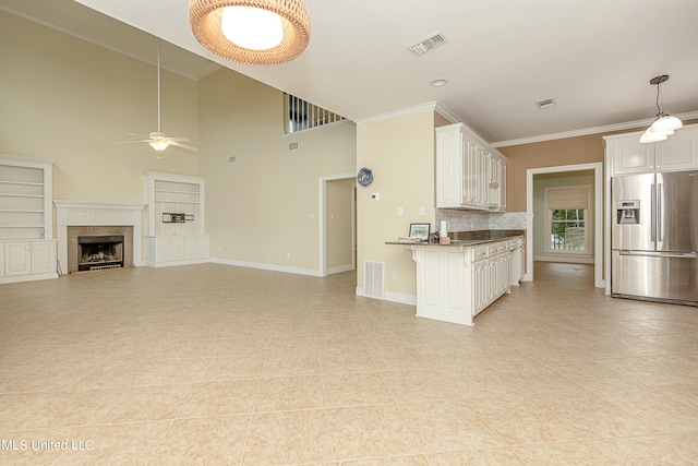 kitchen featuring kitchen peninsula, stainless steel fridge, white cabinets, and ceiling fan