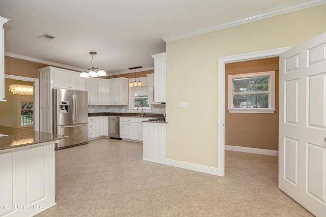 kitchen with appliances with stainless steel finishes, white cabinets, dark stone counters, and pendant lighting