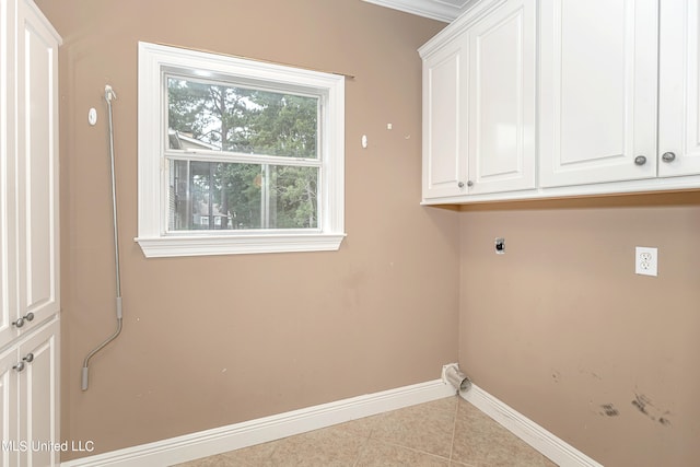 washroom with hookup for an electric dryer, light tile patterned floors, and cabinets