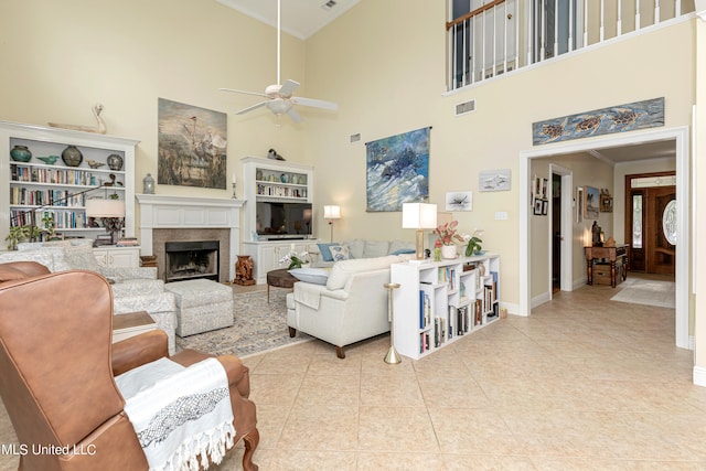 living room with a towering ceiling, crown molding, light tile patterned flooring, and ceiling fan