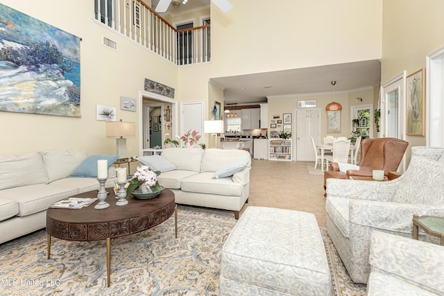 living room with a towering ceiling, ornamental molding, and light carpet