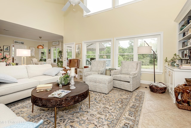 living room with ceiling fan, crown molding, a towering ceiling, and plenty of natural light