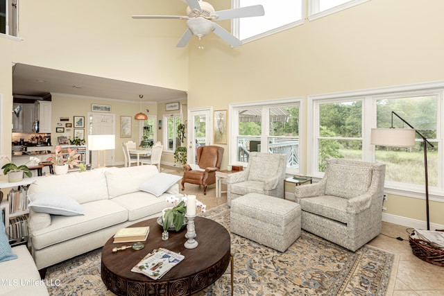 tiled living room with ornamental molding, ceiling fan, a high ceiling, and a wealth of natural light