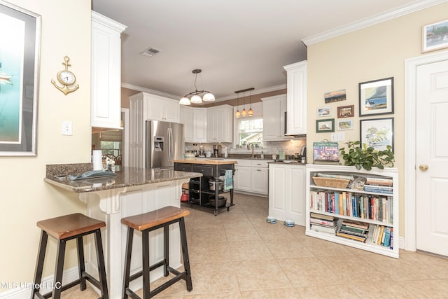 kitchen with white cabinetry, dark stone countertops, tasteful backsplash, and stainless steel refrigerator with ice dispenser