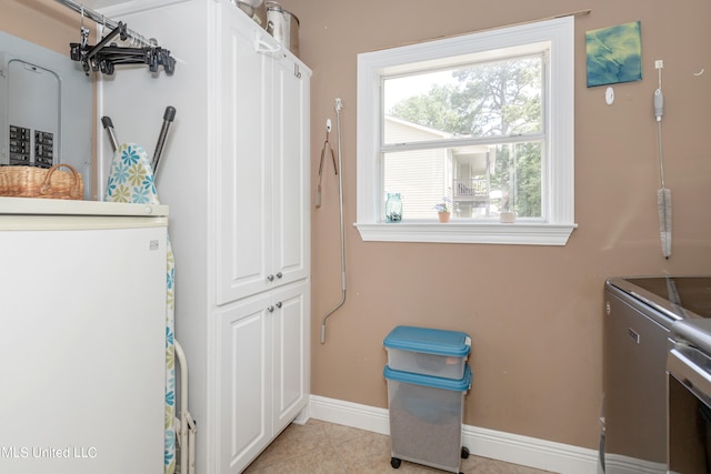 laundry area with light tile patterned flooring, cabinets, and washer and clothes dryer