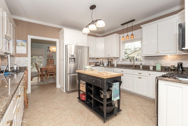 kitchen featuring sink, hanging light fixtures, white cabinets, dark stone countertops, and stainless steel fridge with ice dispenser