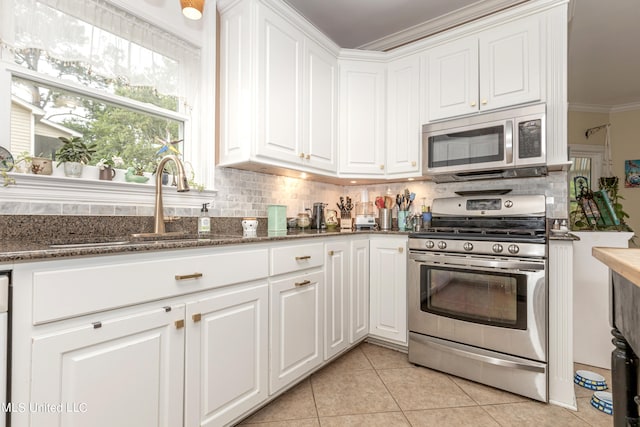 kitchen with crown molding, appliances with stainless steel finishes, white cabinets, and light tile patterned floors