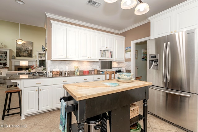 kitchen with white cabinetry, stainless steel fridge, wood counters, and a kitchen breakfast bar