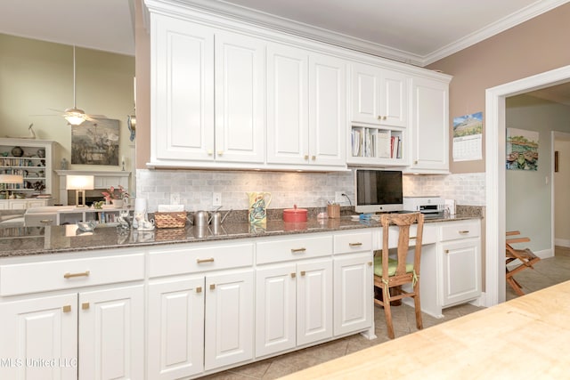 kitchen with dark stone countertops, ornamental molding, light tile patterned floors, white cabinetry, and tasteful backsplash