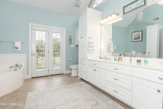 bathroom with a bathing tub, lofted ceiling, toilet, vanity, and tile patterned flooring