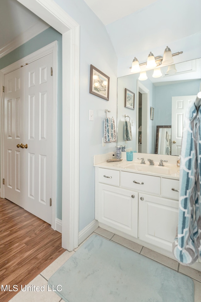 bathroom with vanity, hardwood / wood-style flooring, and vaulted ceiling