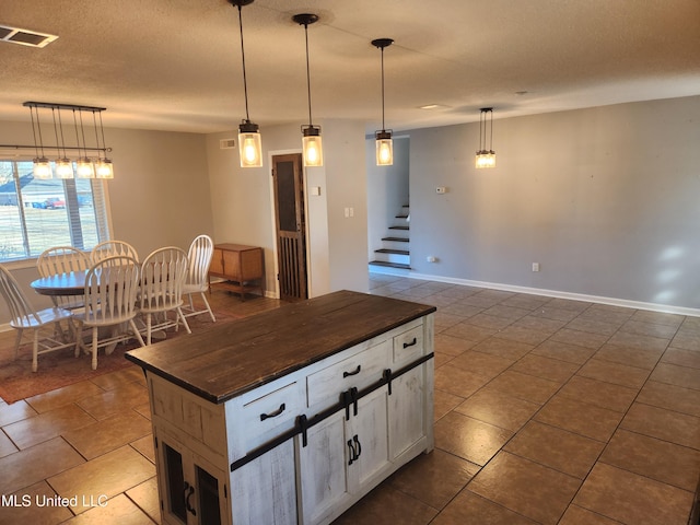 kitchen with a center island, white cabinets, a textured ceiling, and decorative light fixtures