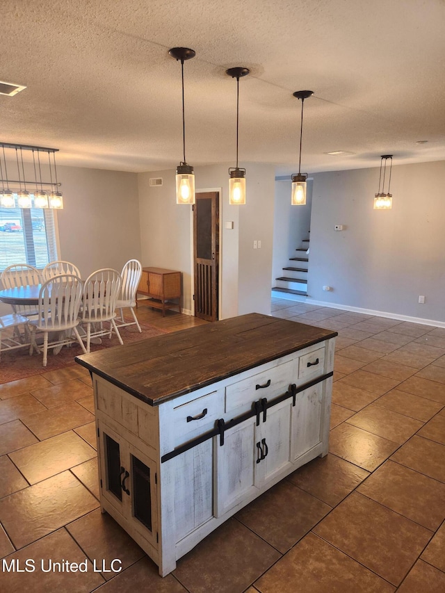 kitchen featuring pendant lighting, dark tile patterned floors, a center island, and a textured ceiling