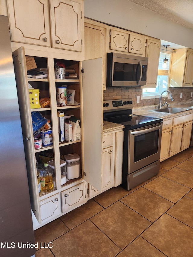 kitchen featuring appliances with stainless steel finishes, dark tile patterned floors, sink, and backsplash