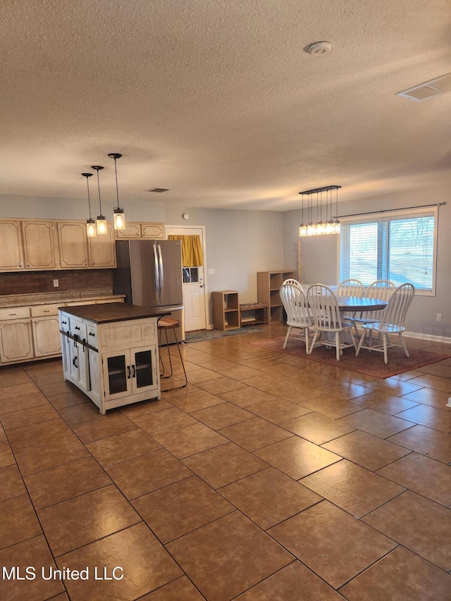 kitchen featuring hanging light fixtures, a center island, stainless steel fridge, and a breakfast bar