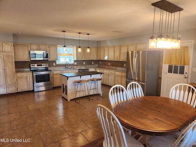 kitchen featuring tasteful backsplash, stainless steel appliances, decorative light fixtures, and a center island