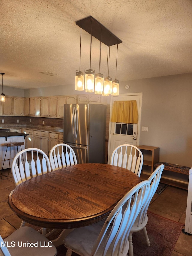 dining area featuring dark tile patterned flooring and a textured ceiling