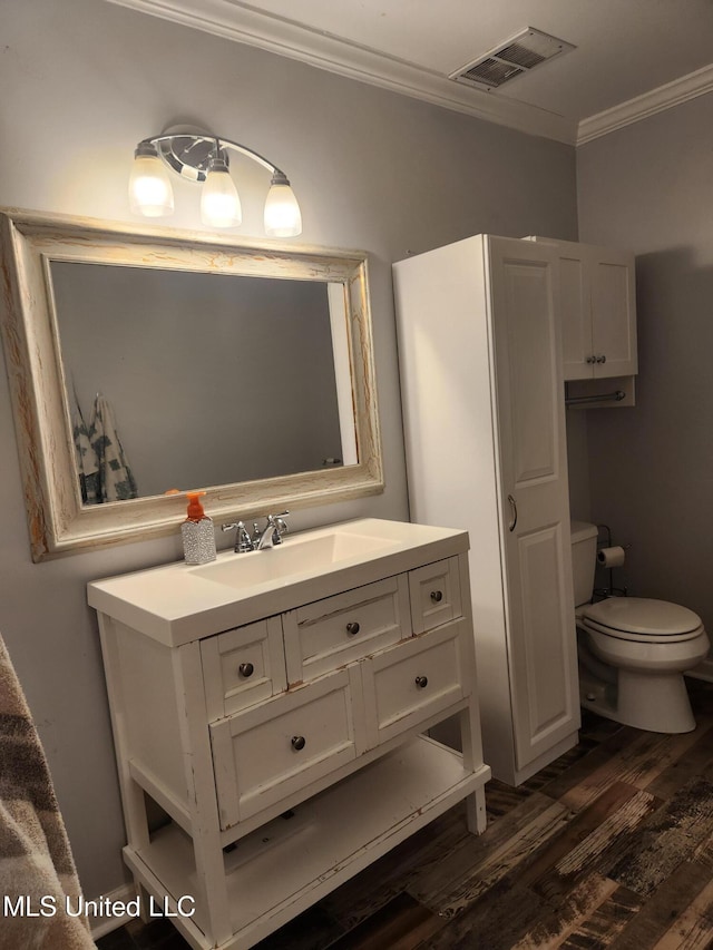 bathroom featuring hardwood / wood-style flooring, ornamental molding, vanity, and toilet