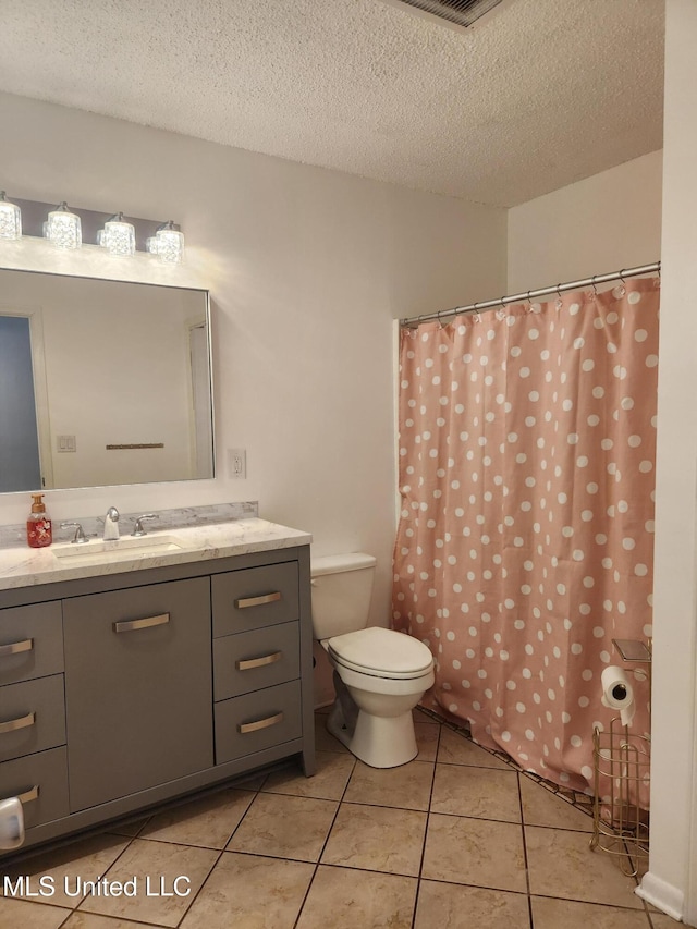 bathroom featuring vanity, tile patterned floors, a textured ceiling, and toilet