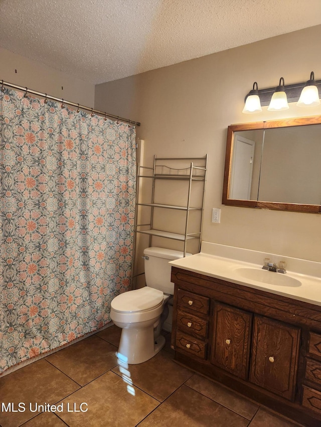 bathroom featuring vanity, toilet, tile patterned flooring, and a textured ceiling