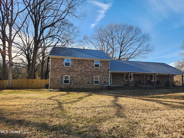 rear view of property with central AC unit and a yard