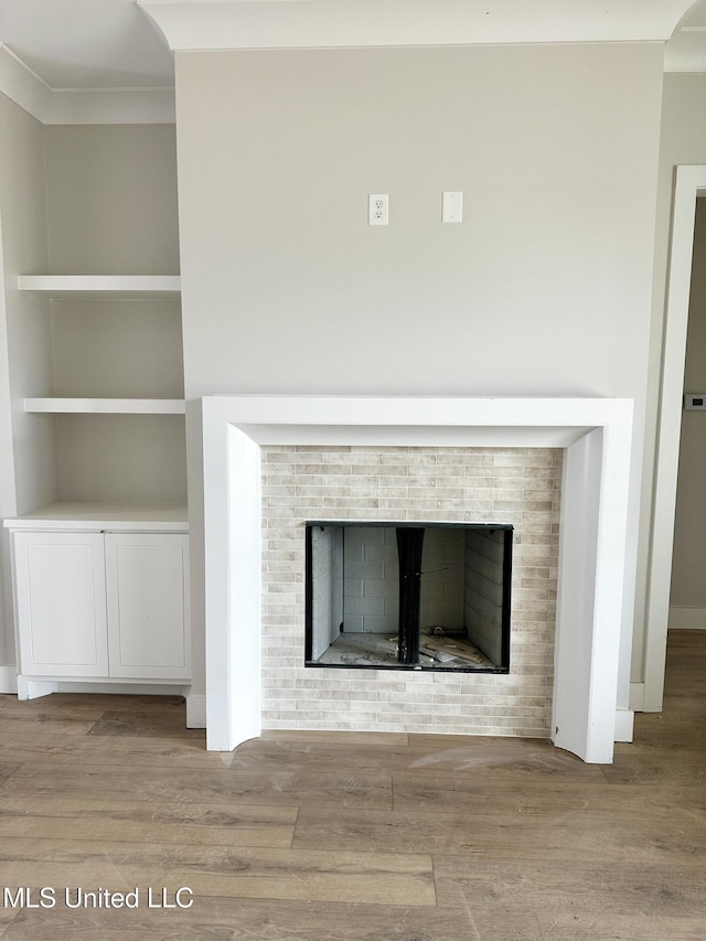 133 Genoa Dr, Madison, MS 39110 - detailed view of a tile fireplace, wood finished floors, crown molding, and built in shelves