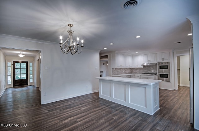 kitchen with crown molding, white cabinetry, dark wood-type flooring, and stainless steel double oven