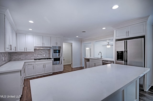 kitchen featuring white cabinets, tasteful backsplash, stainless steel appliances, dark wood-type flooring, and sink