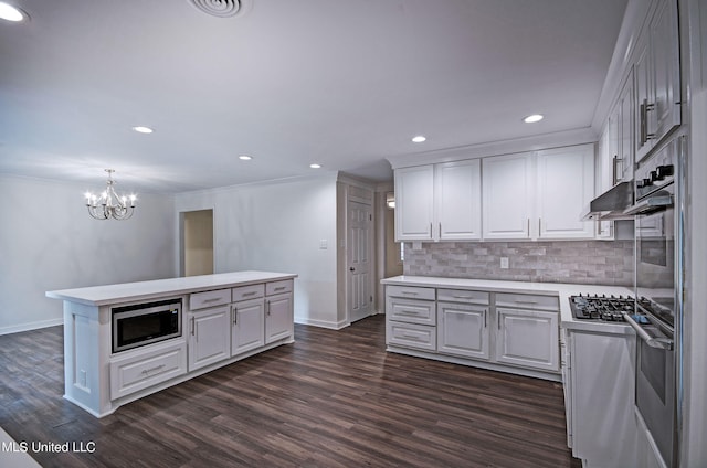 kitchen featuring white cabinetry, stainless steel appliances, dark wood-type flooring, and decorative light fixtures