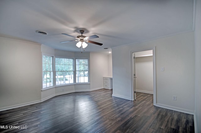 spare room featuring dark wood-type flooring, ceiling fan, and crown molding