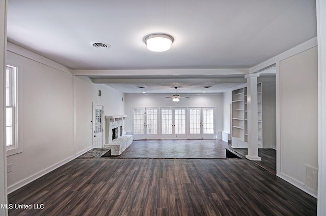 unfurnished living room with dark hardwood / wood-style floors, ceiling fan, built in shelves, and decorative columns