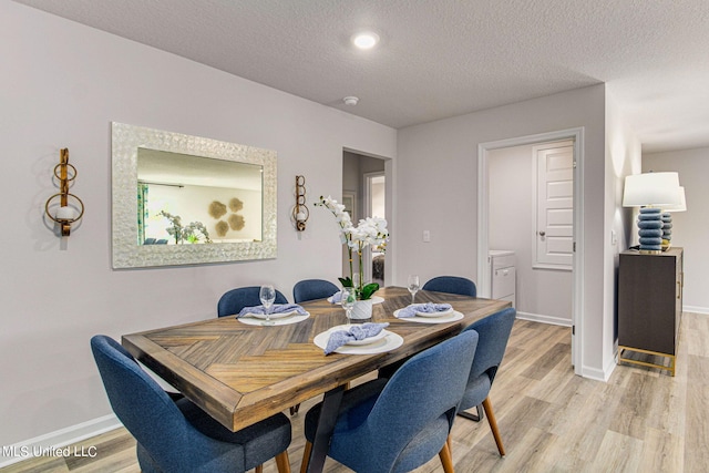 dining area with a textured ceiling and light wood-type flooring