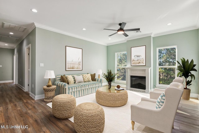 living room with ceiling fan, plenty of natural light, dark wood-type flooring, and ornamental molding