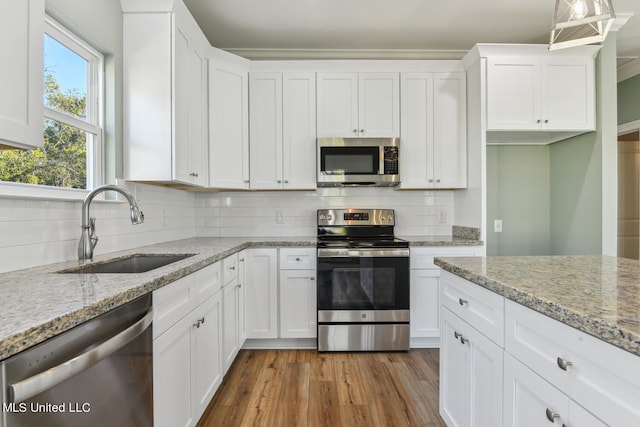 kitchen with tasteful backsplash, stainless steel appliances, sink, light hardwood / wood-style flooring, and white cabinets