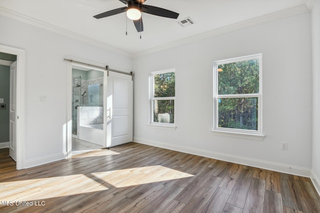 unfurnished bedroom with ensuite bathroom, ceiling fan, a barn door, ornamental molding, and wood-type flooring