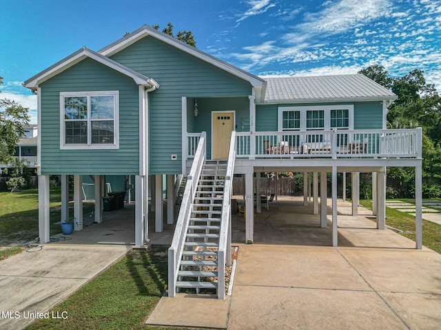 raised beach house with a front yard and a carport