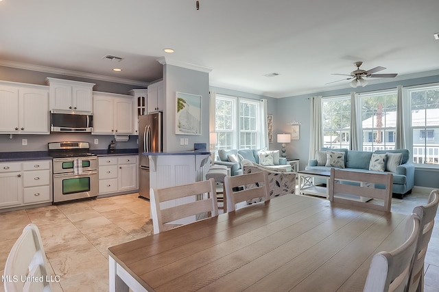 tiled dining area featuring ornamental molding, ceiling fan, and plenty of natural light