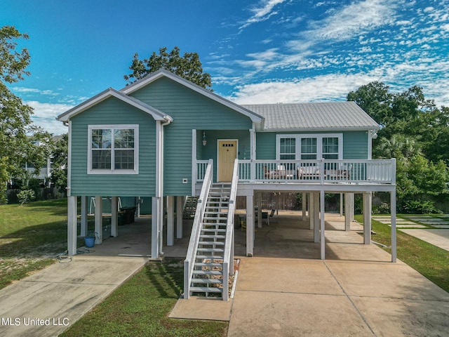 beach home with a porch, a front lawn, and a carport