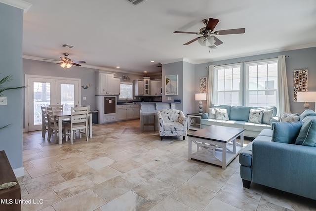 living room featuring crown molding, a healthy amount of sunlight, and ceiling fan