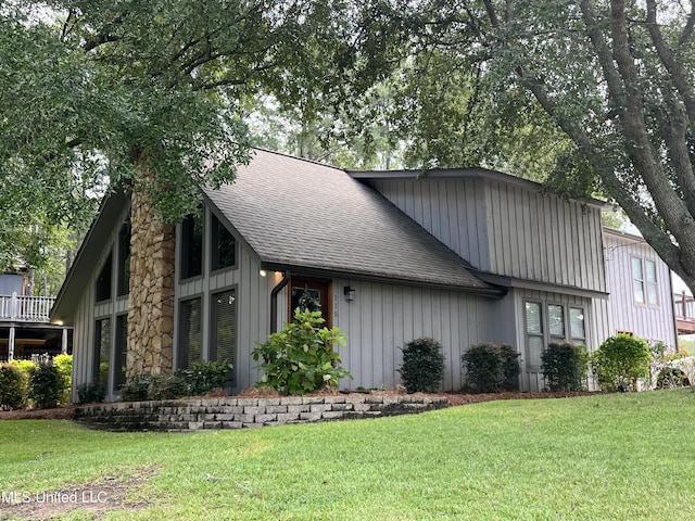 view of side of property featuring a shingled roof, a lawn, and board and batten siding